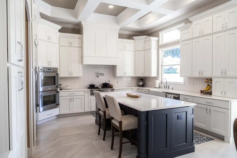 Kitchen remodeling Oviedo FL by Stevens Kitchens: white shaker cabinets up to a coffered ceiling, navy island with white quartz and double wall ovens